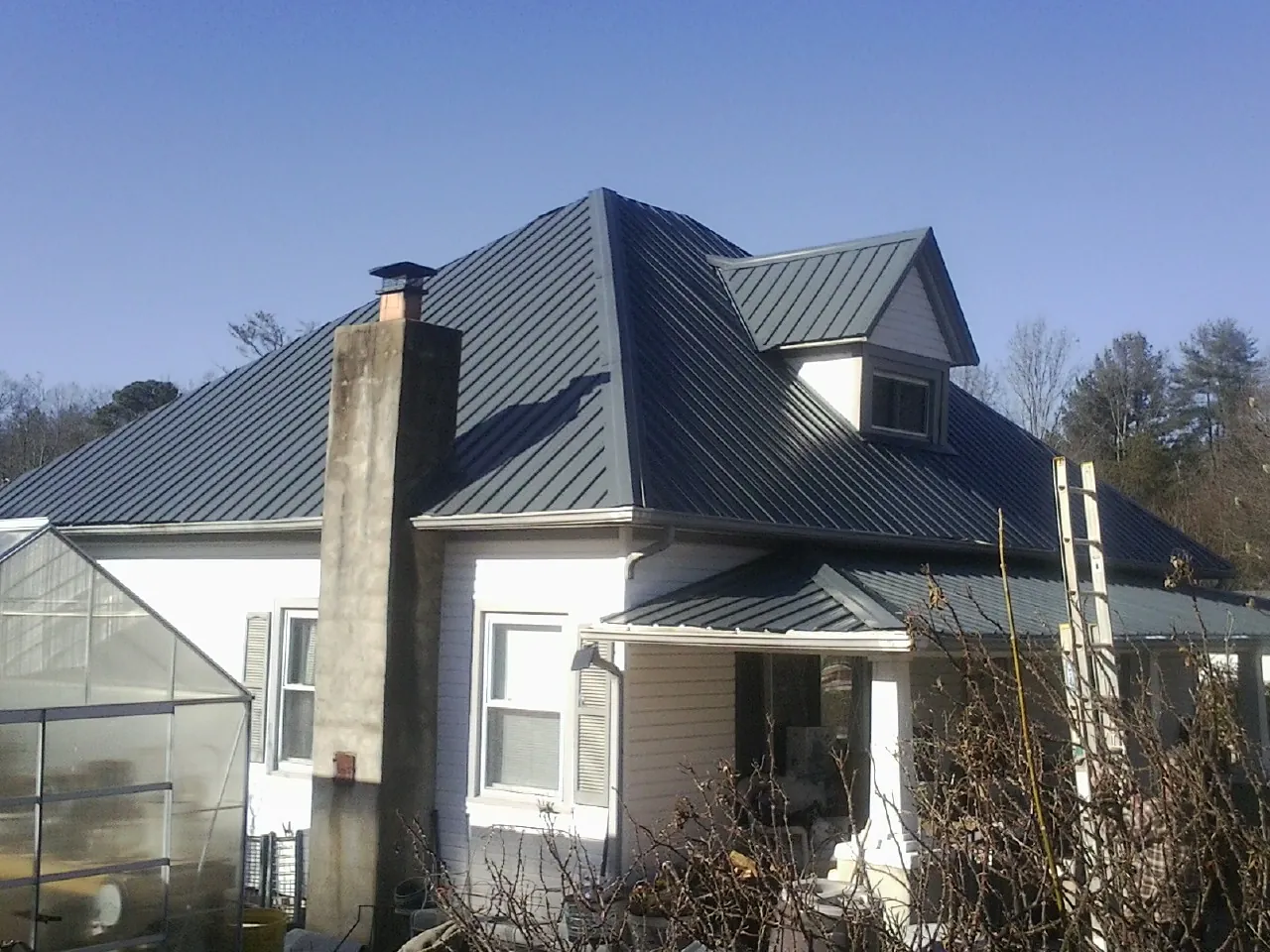 Dark blue standing seam metal roof on a white farmhouse with dormer — Slate & Tile Roof Repair by Roofing Brothers in Newburgh