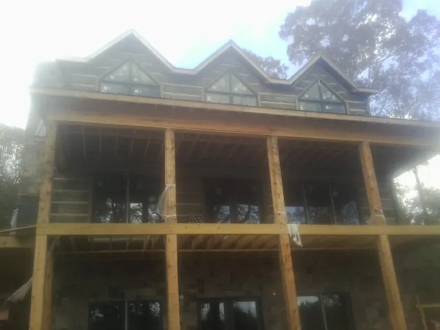 Dormers and porch framing on a large log home under construction — Roof Coating work by our crew in Newburgh