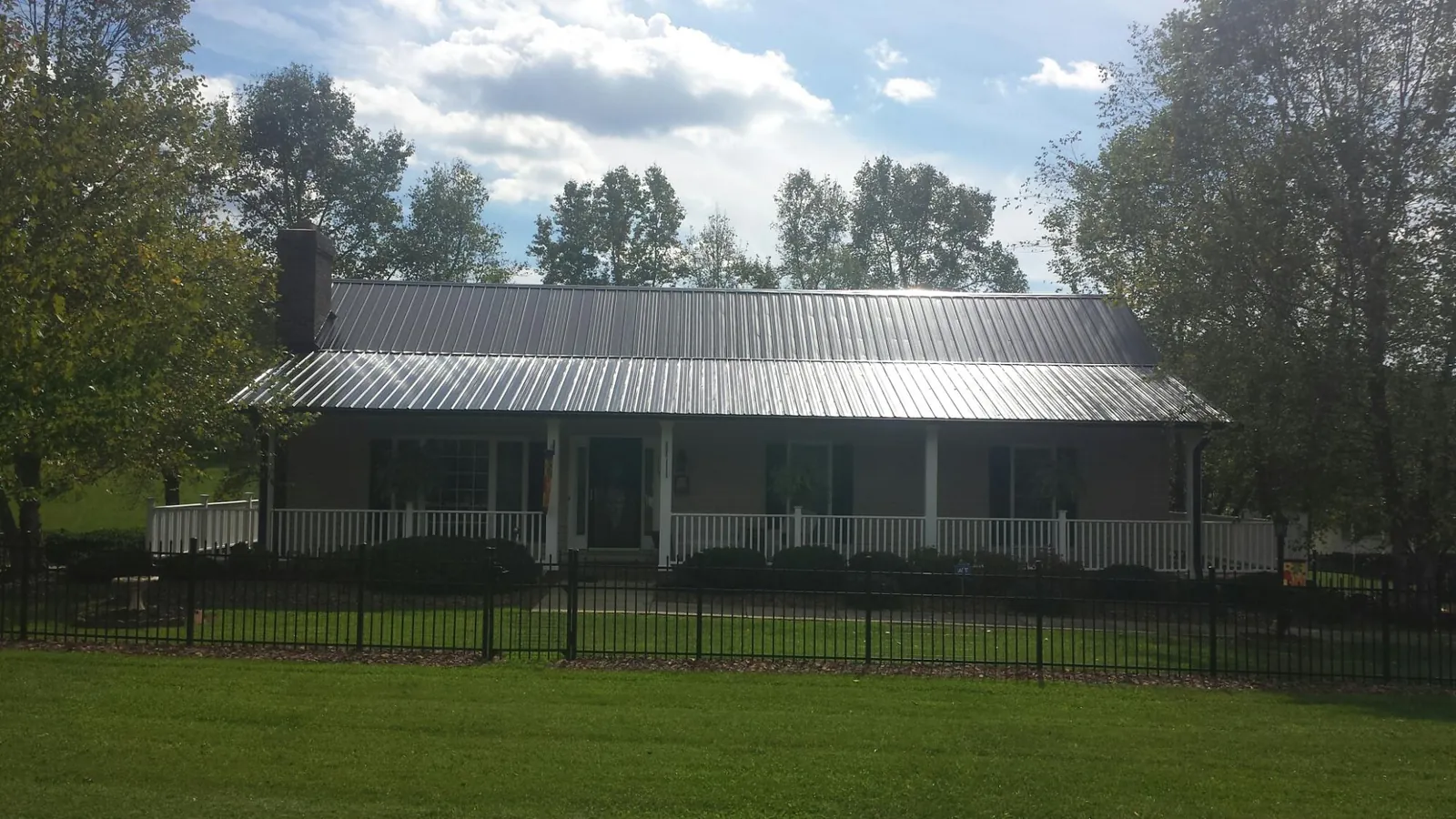 Gray metal roof on a brick ranch with a full width front porch — Gutter Guard Installation work by our crew in Newburgh