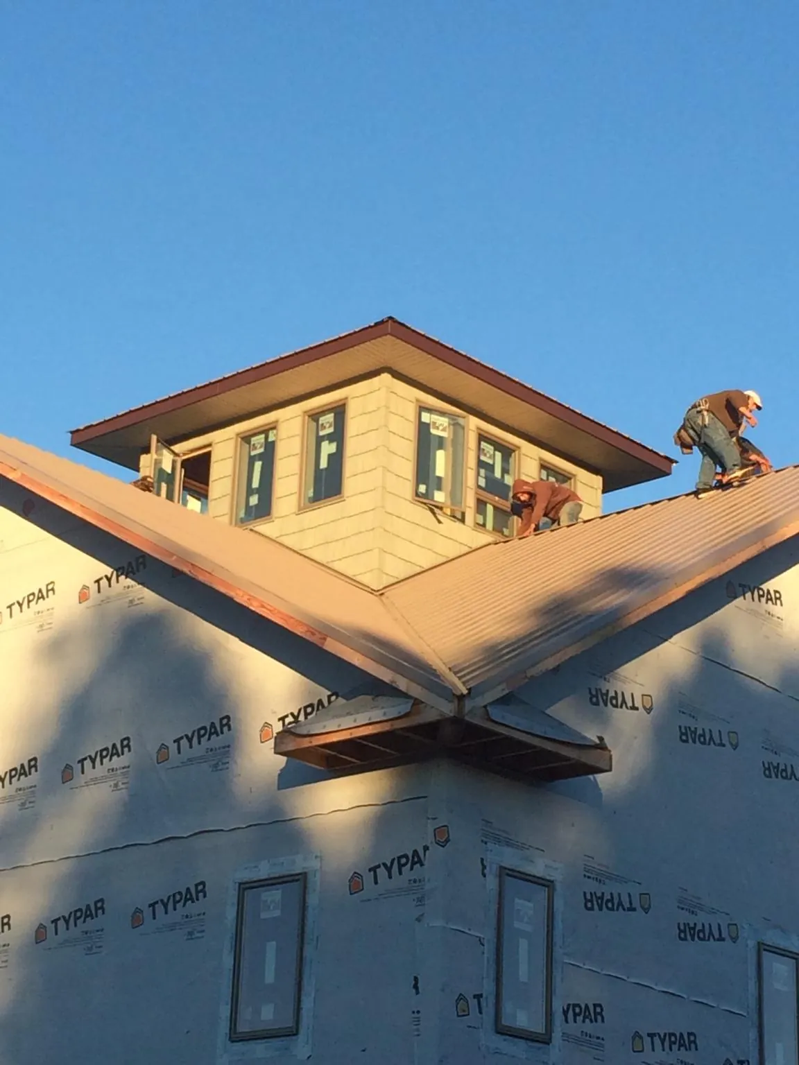 Roofers working around a rooftop cupola on a new metal roof at sunset — Roof Waterproofing in Newburgh by Roofing Brothers